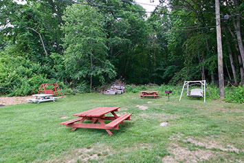 picnic tables and swing in the green lawn against the trees